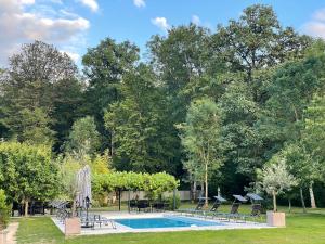 a swimming pool with chairs and a table and trees at Sweethome – La Jacqueminière in Courtenay