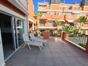 un balcón con 2 sillas blancas y un edificio en Sunset apartment en El Guincho