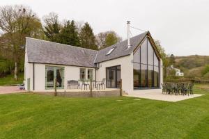 a white house with tables and chairs in a yard at Balbeg Cottage in Straiton