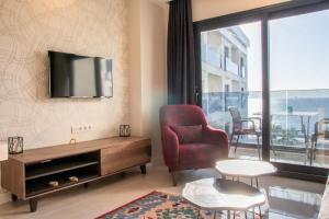 a living room with a chair and a tv on the wall at Sea View Flat w Pool 1 min to Beach in Kusadasi in Kusadası
