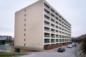 ein weißes Gebäude mit Autos auf einem Parkplatz in der Unterkunft Lakeview Modern Condo-Tennis, Parking, Balcony in Cluj-Napoca