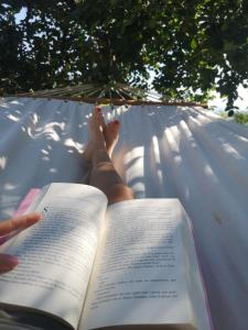 Villa Calcerame في Montelepre: شخص يستلقي على أرجوحة يقرا كتاب