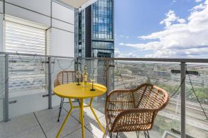 a yellow table and two chairs on a balcony at 14th Floor City Center View Apartment Towarowa 37 by Renters in Poznań