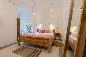 a bedroom with a bed with orange sheets and pink pillows at NETS Cowork & Colive in Ahangama