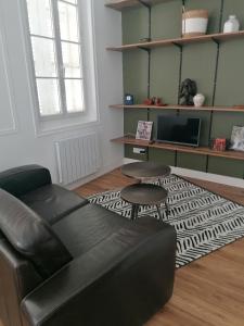 sala de estar con sofá de cuero negro y alfombra en Le Tréville Grand Studio Cosy 32M2, en Rochefort
