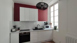 cocina con armarios blancos, fregadero y ventana en Le Tréville Grand Studio Cosy 32M2, en Rochefort