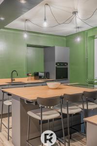 una cocina con paredes verdes y una gran isla con sillas en R'Apparts T4 Urban Loft, en Noyarey