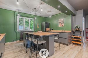 a kitchen with green walls and a island with bar stools at R'Apparts T4 Urban Loft in Noyarey