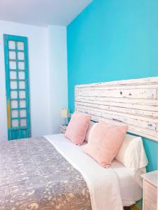 - une chambre bleue avec un lit et 2 oreillers roses dans l'établissement Triana Home Luxury, à Séville