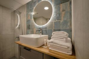 ein Badezimmer mit einem Waschbecken, einem Spiegel und Handtüchern in der Unterkunft Queen Barbora Central Lofts in Kaunas