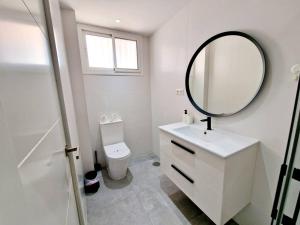 a white bathroom with a mirror and a toilet at Ground floor Apt in La Cala in Mijas Costa +16 photos