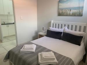 a bedroom with a bed with two towels on it at OysterCatcher Self-Catering Accommodation Strand in Cape Town +69 photos