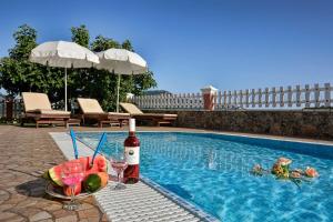 a bottle of wine and a plate of fruit next to a swimming pool at Tranquil Corfu Villa - 3 Bedrooms - Villa Chrinos - Gated Pool - Agios Georgios Pagon in Agios Georgios Pagon