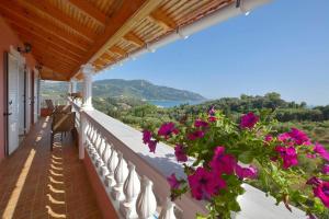 a balcony with flowers and a view of the ocean at Tranquil Corfu Villa - 3 Bedrooms - Villa Chrinos - Gated Pool - Agios Georgios Pagon in Agios Georgios Pagon
