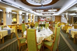 ロジュノフ・ポト・ラドホシュチェムにあるWellness Hotel Eroplánの白いテーブルと黄色の椅子とテーブル、テーブルサーチャーが備わるレストラン