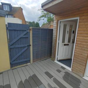 een blauwe poort op een houten terras met een deur bij Self Contained, Garden Studio walking distance to Harry Potter Studio in Leavesden Green
