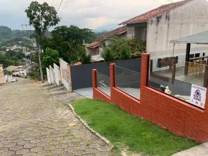 a house with a red brick wall and a yard at Hostel SIL CARDOSO in Blumenau