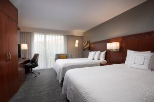 a hotel room with two beds and a desk at Courtyard by Marriott Bradenton Sarasota/Riverfront in Bradenton