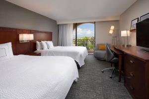 ブレーデントンにあるCourtyard by Marriott Bradenton Sarasota/Riverfrontのベッド2台とデスクが備わるホテルルームです。