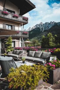 une terrasse avec des canapés et des fleurs devant un bâtiment dans l'établissement Hotel Toblacherhof, à Dobbiaco