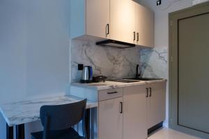 a kitchen with white cabinets and a table and a chair at Sky View Suites Kefalonia in Vóvikes