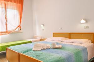 a bedroom with two beds and two towels on a bed at Hotel Gialpina in Rimini
