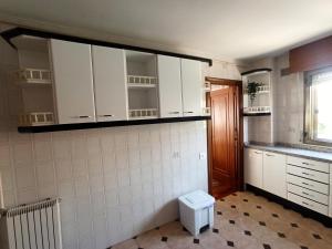 una cocina con armarios blancos y un aseo. en LA BOTICA DEL MONASTERIO, en Sahagún