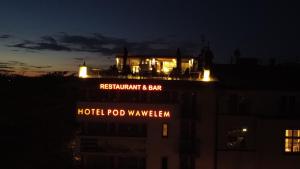 a building with a sign on top of it at night at Hotel Pod Wawelem in Krakow