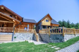 a log home with a stone retaining wall and a wooden fence at PENSIUNEA IZABELLA, Izabella Chalet in Topliţa
