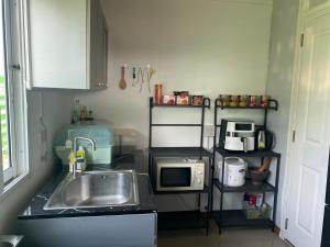 uma pequena cozinha com um lavatório e um micro-ondas em Airport Bangkok Villa em Ban Siyek Hua Take