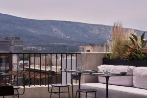 a balcony with a couch and tables and chairs at The Newel Psychiko in Athens