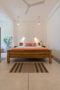 a bedroom with a large wooden bed with pink pillows at NETS Cowork & Colive in Ahangama
