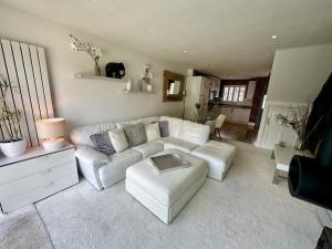 Fantastic 2-Bed House with Parking - Hosted by Hutch Lifestyle في ليمينغتون سبا: غرفة معيشة مع أريكة بيضاء وطاولة