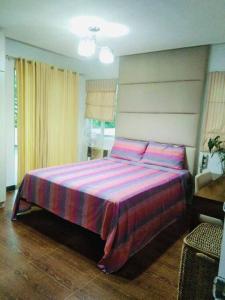 1 dormitorio con 1 cama con manta rosa y morada en Melia's House Tagaytay - Nature Home for Rent, en Tagaytay