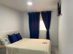 a bedroom with a bed with blue curtains and a window at Alojamiento con habitaciones dobles y baño privado in Valencia