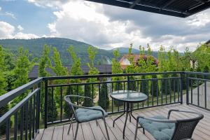 a balcony with a table and chairs and mountains at Szczyrkowskie SKI & FUN z widokiem na góry sauna, jacuzzi in Szczyrk