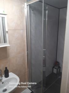 a shower with a glass door next to a sink at 145 Burnley Road in London