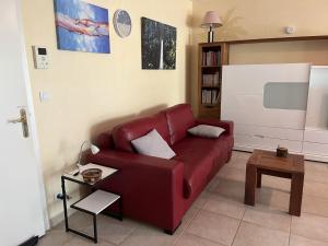 a living room with a red couch and a table at Saint-Raphaël, Boulouris, F2 dans belle résidence 3 piscines, proche bord de mer in Saint-Raphaël