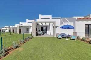 a house with a yard with two chairs and an umbrella at The Villa in Vilamoura