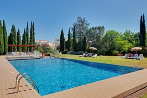 uma grande piscina num quintal com árvores em The Villa em Vilamoura