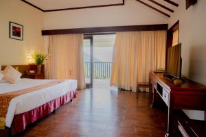 a hotel room with a bed and a flat screen tv at Belvedere Tam Dao Resort in Tam Ðảo