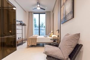 una camera con un letto e una sedia e una finestra di Magnificent Renovated 2BD 2BTH Duplex with Backyard - City Centre a Málaga