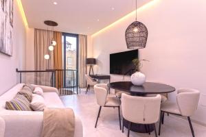 ein Wohnzimmer mit einem Sofa, einem Tisch und Stühlen in der Unterkunft Magnificent Renovated 2BD 2BTH Duplex with Backyard - City Centre in Málaga
