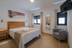 a bedroom with a bed and a chair and a television at Sol da Vila in Vila Nova de Milfontes