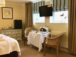 um quarto de hotel com uma mesa e cadeiras e uma televisão em Fernbank em Shanklin