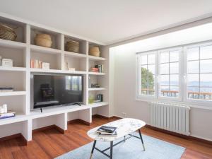 sala de estar blanca con TV y silla en housingcoruña ZAPATEIRA, en A Coruña
