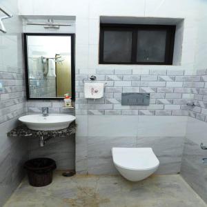 een badkamer met een wastafel, een toilet en een spiegel bij HOTEL MAYURA in Ajmer