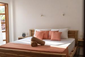 a bedroom with a large bed with pink pillows at NETS Cowork & Colive in Ahangama