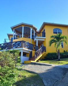 a yellow house with a palm tree in front of it at Bellevue hideaway in Gros Islet