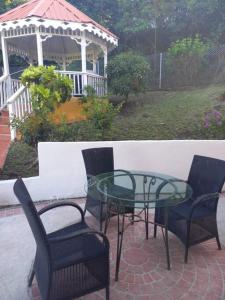a glass table and chairs on a patio with a gazebo at Bellevue hideaway in Gros Islet